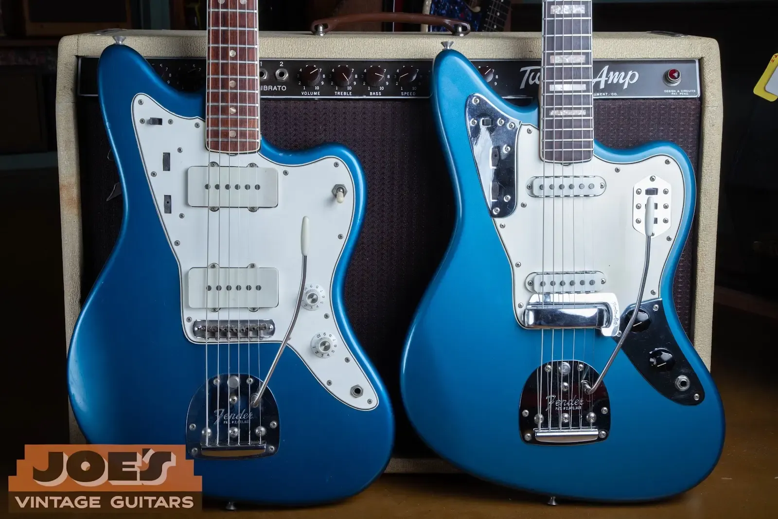 Two right-handed blue vintage Fender offset guitars photographed in front of a Fender amplifier