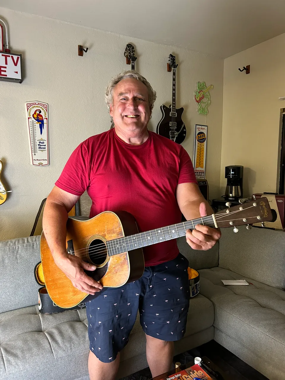Steve Minnich smiling while holding the worn 1955 Martin D-28 his father bought new