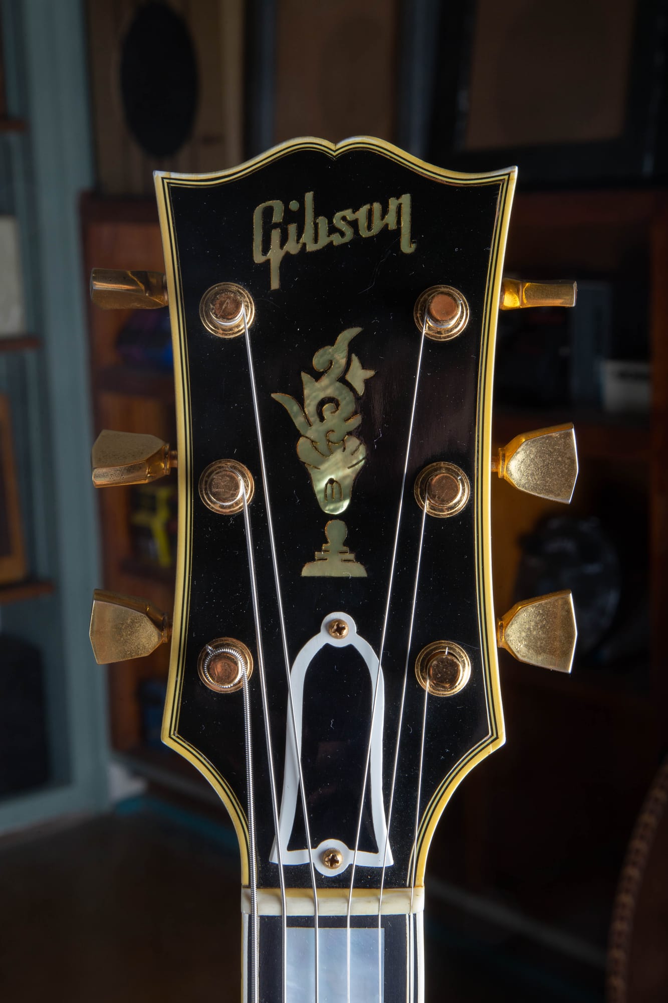 Headstock of a 1957 Gibson Byrdland showing the pearl flowerpot inlay and pearl Gibson script logo, gold tuners