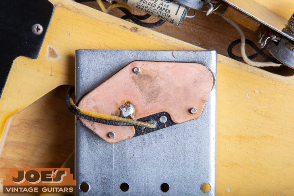Rear view of an original 1952 Fender Telecaster bridge pickup showing the copper-plated steel baseplate and cloth-covered lead wires.
