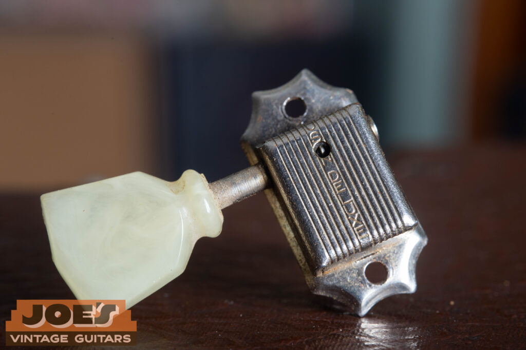 Close-up of a 1956 Gibson Les Paul Kluson Deluxe "Single Line" tuner housing, showing the "Kluson Deluxe" stamp and an aged cream tulip button.