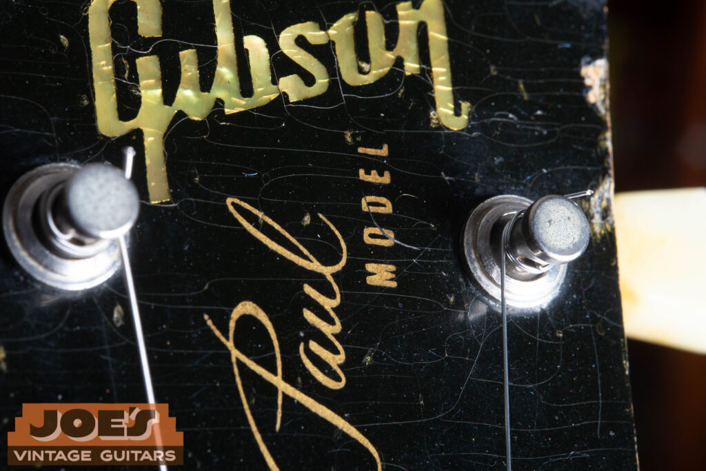 Close-up of a 1956 Gibson Les Paul headstock featuring the Mother of Pearl Gibson inlay and the gold "Les Paul Model" silkscreen, showing the specific mid-50s font and the vertical spacing between the logo and the script.