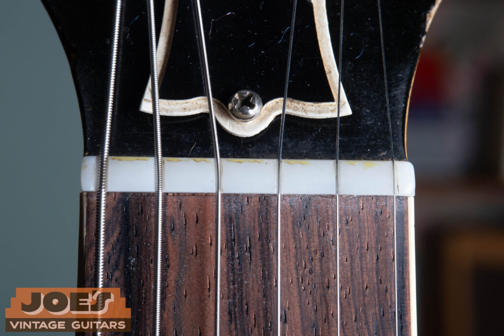 Macro close-up of a 1956 Gibson Les Paul original nut made of Nylon 6/6, showing the characteristic off-white translucent color and period-correct string slotting.
