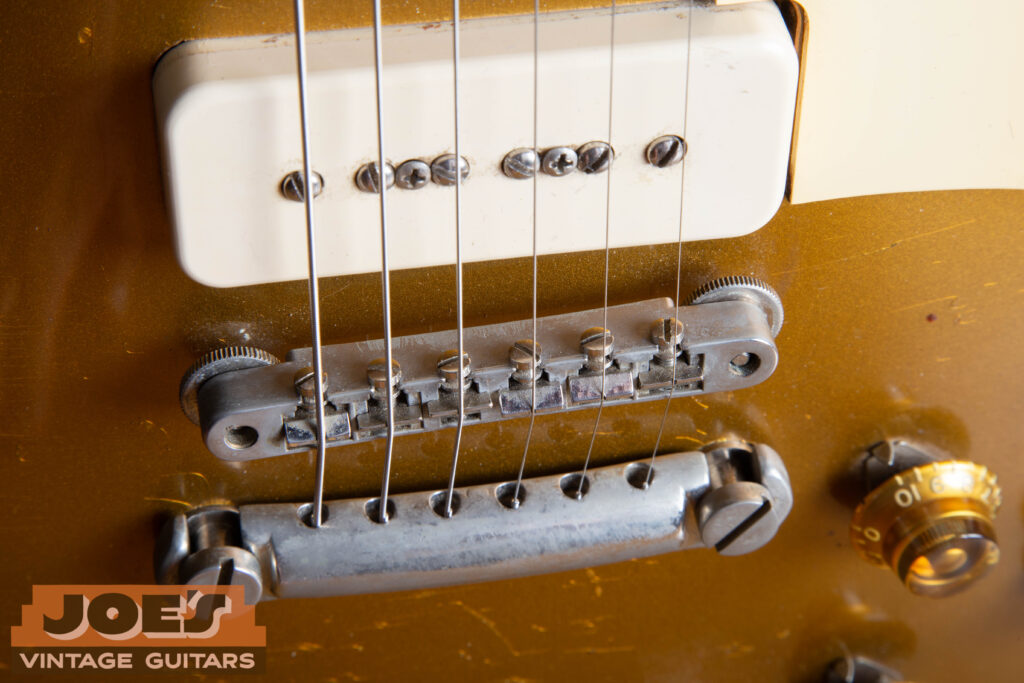 Top-down close-up of a 1956 Gibson Les Paul ABR-1 Tune-o-matic bridge, highlighting the "no-wire" design with nickel-plated saddles and thumbwheels.