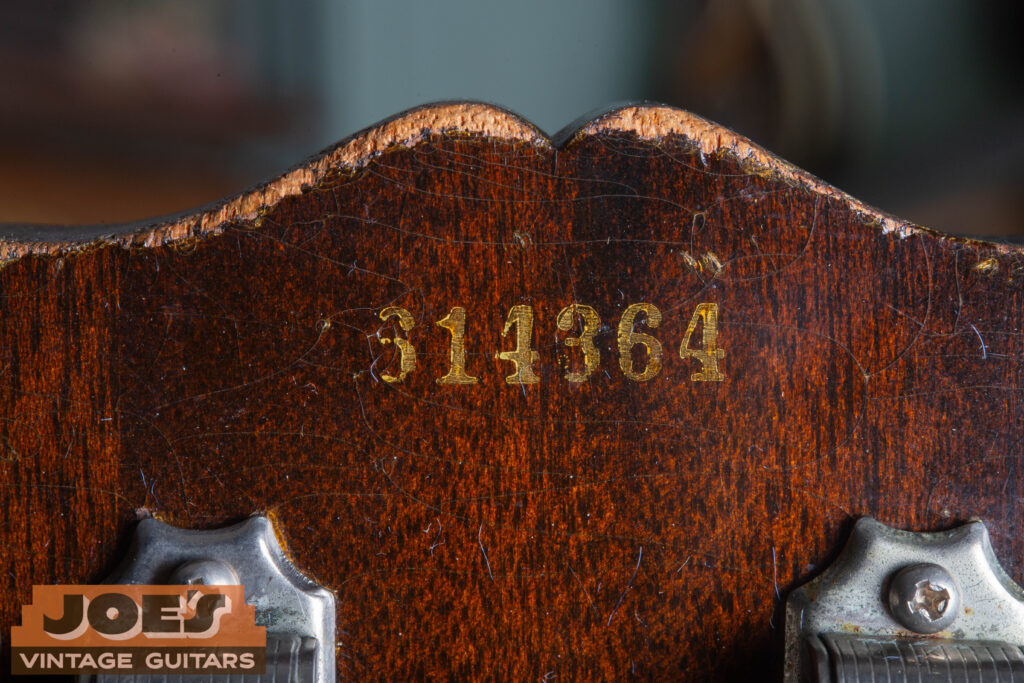 Macro close-up of a 1956 Gibson Les Paul serial number ink-stamped in black on the back of the headstock, showing the "6" prefix and the characteristic blocky mid-50s typeface.