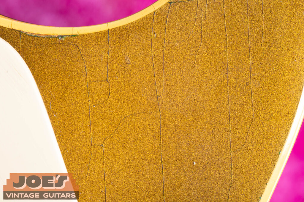 Macro close-up of a 1957 Gibson Les Paul Goldtop bullion gold finish, showing fine weather checking and subtle green oxidation from aged bronze powder lacquer.