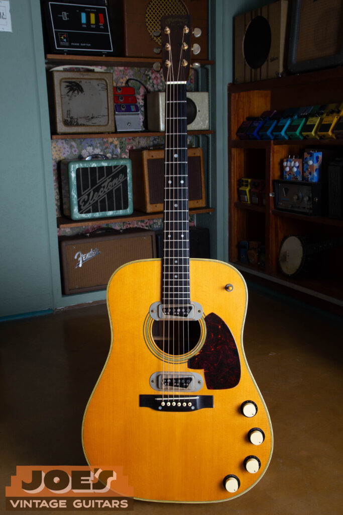 A full-length frontal shot of a 1959 Martin D-28E vintage acoustic-electric guitar, showcasing the dreadnought body shape, dual factory DeArmond pickups, and original gold hardware.