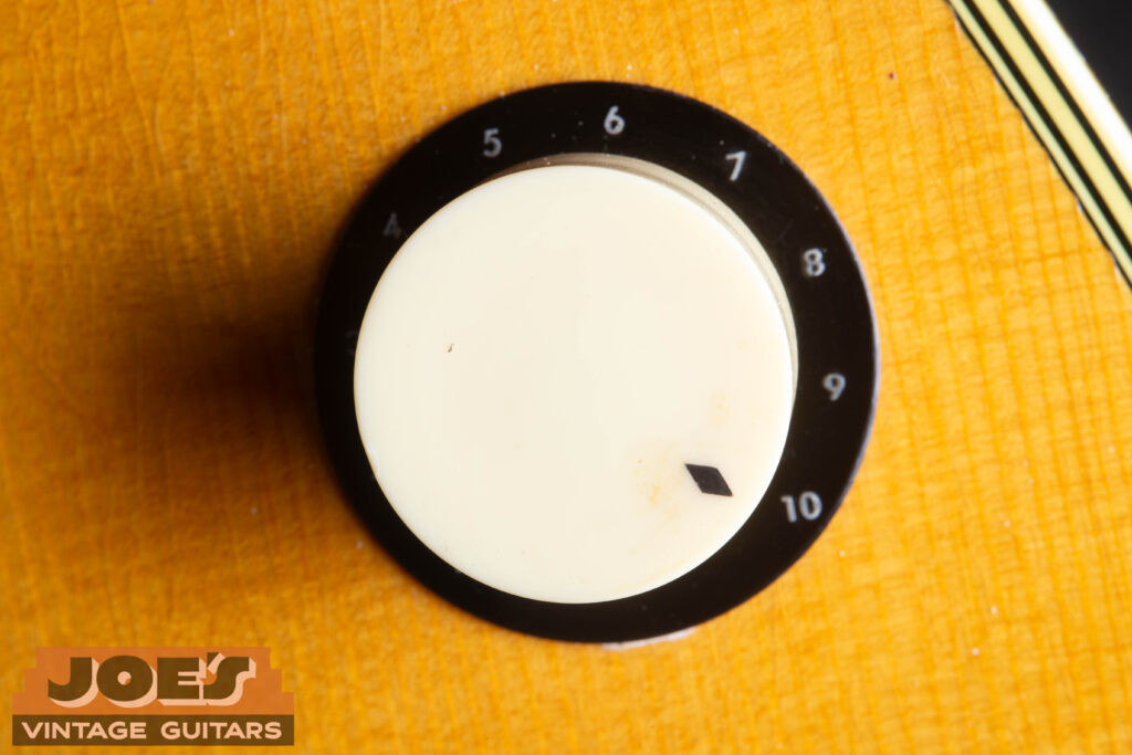 Close-up of a vintage white "cup" style control knob on a 1959 Martin D-28E, showcasing the original period-correct hardware and gold-plated components.