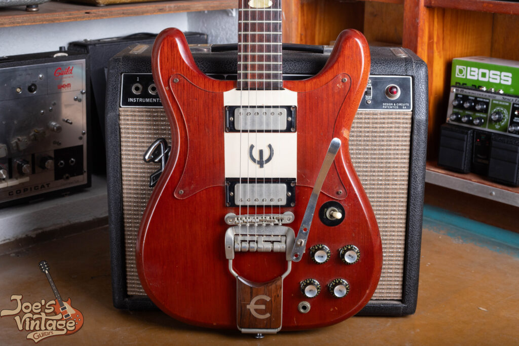 A detailed body shot of a 1961 Epiphone Crestwood, highlighting the symmetrical mahogany double-cutaway, dual mini-humbucker pickups, and original cherry finish.