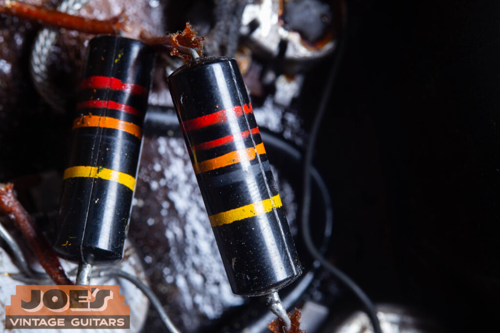 An internal view of the 1957 control cavity showing the original Sprague "Bumblebee" capacitors with their iconic color-coded stripes and .022uF 400V ratings.