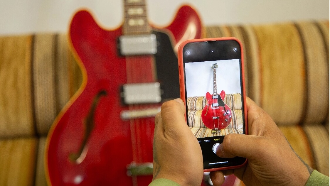 Man Taking A Clear Photo Of A Cherry Gibson ES-335 To Show Brand And Model