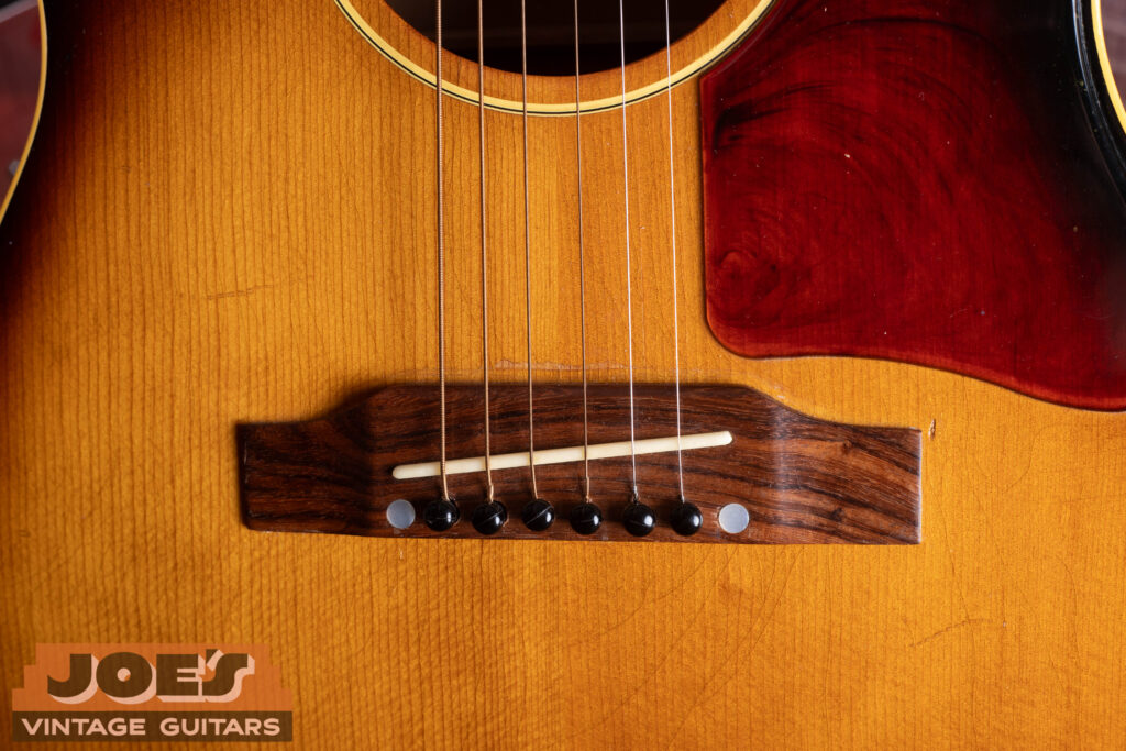 Close up of vintage Gibson LG-1 belly up rosewood bridge with original bridge pins and saddle detail.