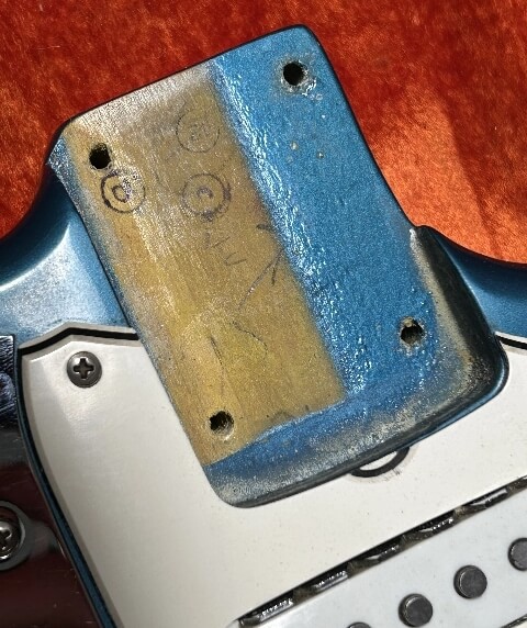 Close-up of a vintage guitar neck pocket showing aged with a Lake Placid Blue finish visible on the body.