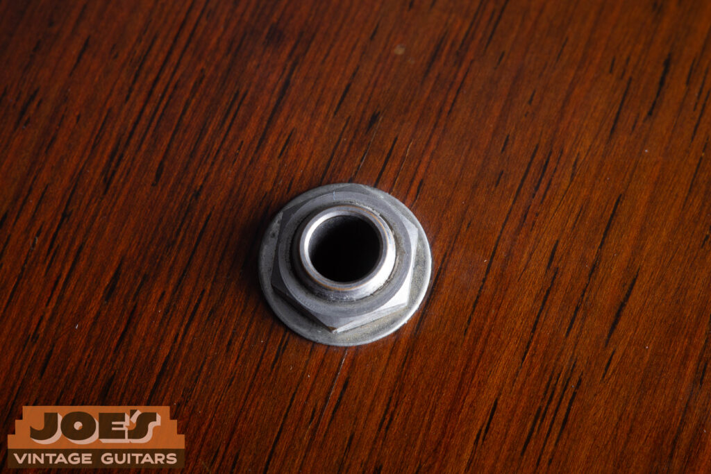 Side-view close-up of the factory-original 1/4 inch output jack on a 1959 Martin D-28E vintage guitar, mounted on the lower bout