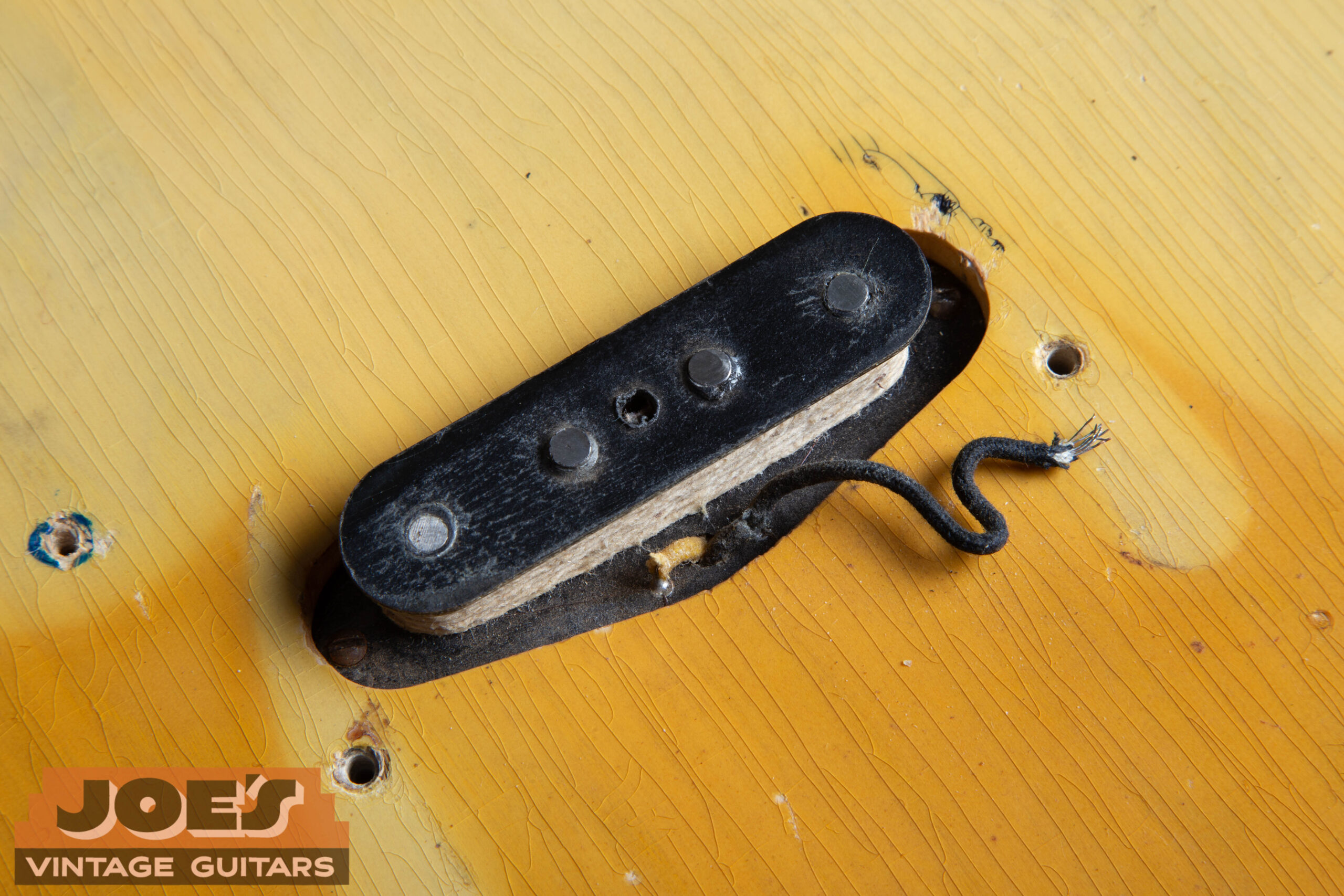 Original early-style single-coil pickup on a 1952 Fender Precision Bass showing white string wrapping over the coil windings