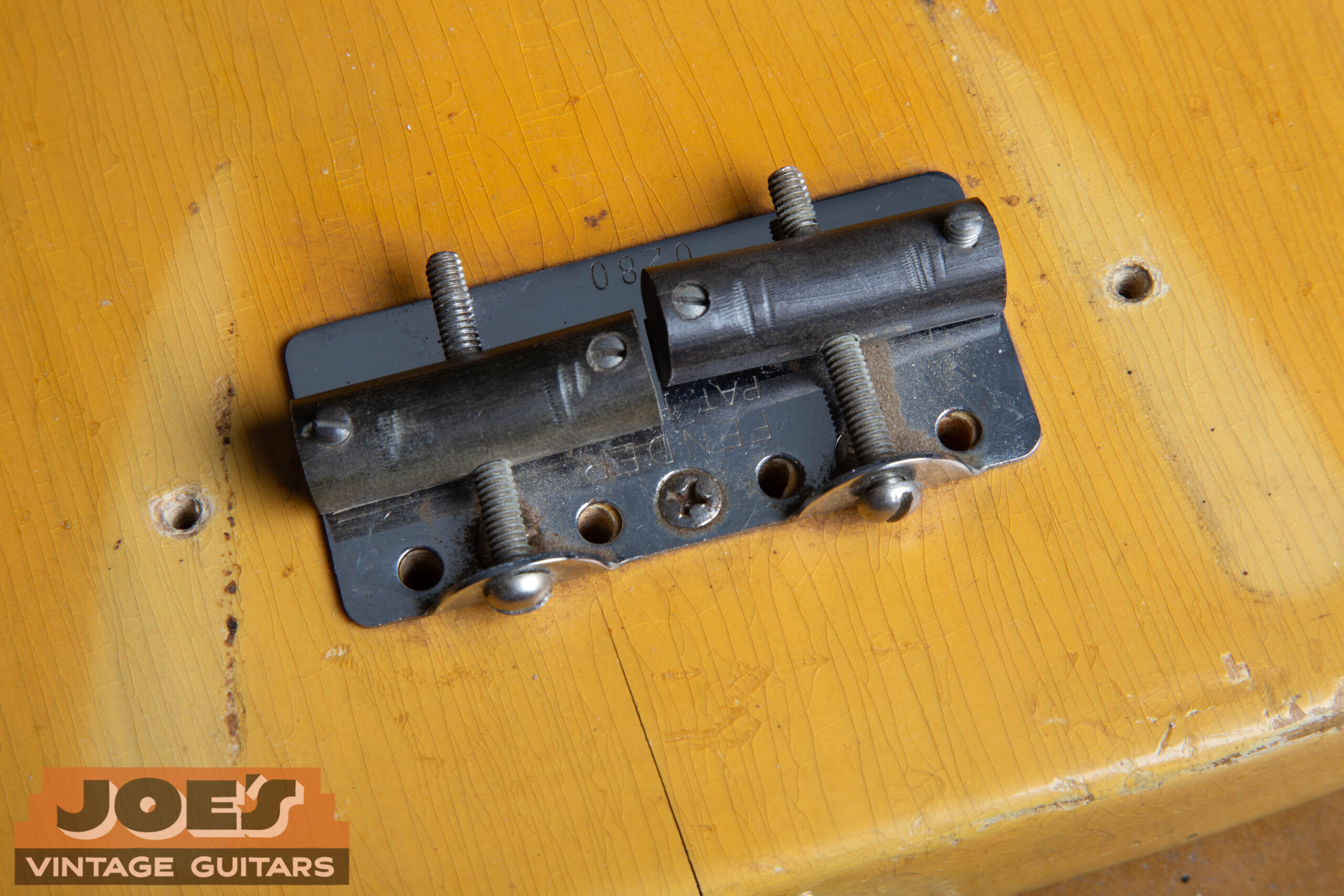 Bridge and saddles on a 1953 Fender Precision Bass showing the pressed fiber barrel saddles, serial number stamp, and Patent Pending marking