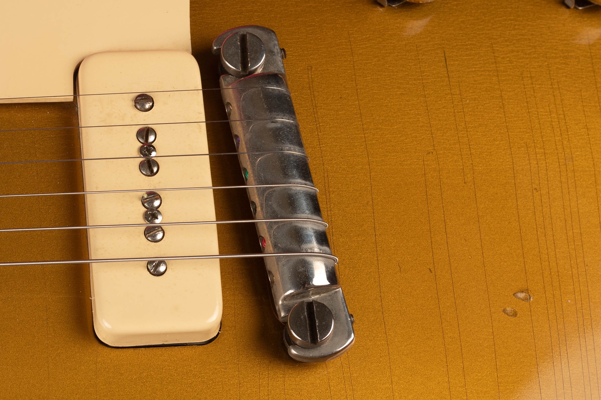 1954 Gibson Les Paul Goldtop wrap tail bridge close-up — nickel-plated stud bar bridge with threaded posts and original shorter bushings