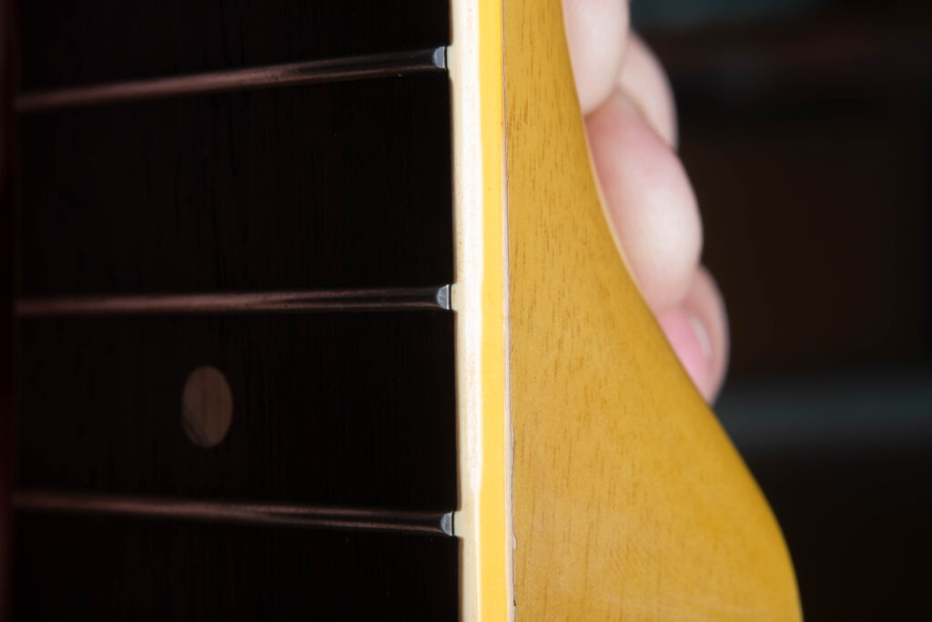 Detailed side-profile view of the neck binding on a 1958 Gibson Les Paul Special. The image shows the original "fret nibs," where the plastic binding material rolls up to cover the ends of the frets. This feature confirms the instrument has its factory-original frets, as the nibs are typically lost during a professional refret.
