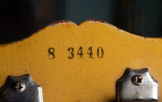 Detailed view of the back of a 1958 Gibson Les Paul Special headstock featuring the original black ink-stamped serial number. The Five-digit sequence is applied on top of the "TV Yellow" nitrocellulose finish, showing a distinct, slightly fuzzy edge characteristic of 1950s factory stamping rather than a modern impression into the wood.