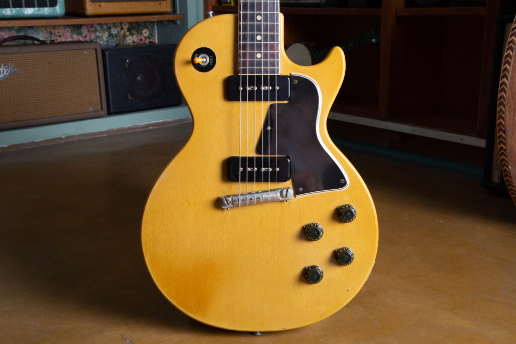 Front body view of an authentic 1958 Gibson Les Paul Special in original TV Yellow limed mahogany finish. Detail shows two black P-90 soapbar pickups, a nickel-plated short-seam wraparound tailpiece with original intonation Allen screws, 5-ply black pickguard, and four black top-hat knobs. The mahogany wood grain is visible through the translucent nitrocellulose lacquer with natural weather checking.