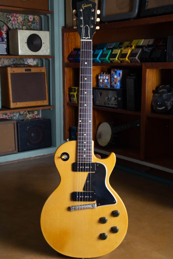 Full-body studio photograph of a 1958 Gibson Les Paul Special in its original TV Yellow (limed mahogany) finish. The single-cutaway mahogany slab body is shown from the front, highlighting the dual P-90 soapbar pickups, wraparound tailpiece, black "top hat" knobs, and the 5-ply pickguard. The bound mahogany neck and headstock with original Kluson strip tuners complete the factory-correct silhouette of this "Golden Era" instrument.