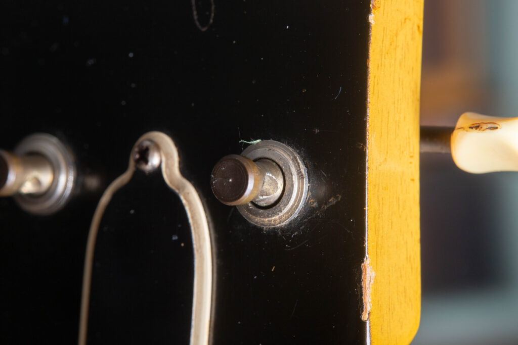 Macro photograph of a 1950s Kluson Deluxe tuner post on a Gibson Les Paul Special. The image focuses on the original brass post, which has oxidized over 70 years to a deep, dark bronze and matte black patina.