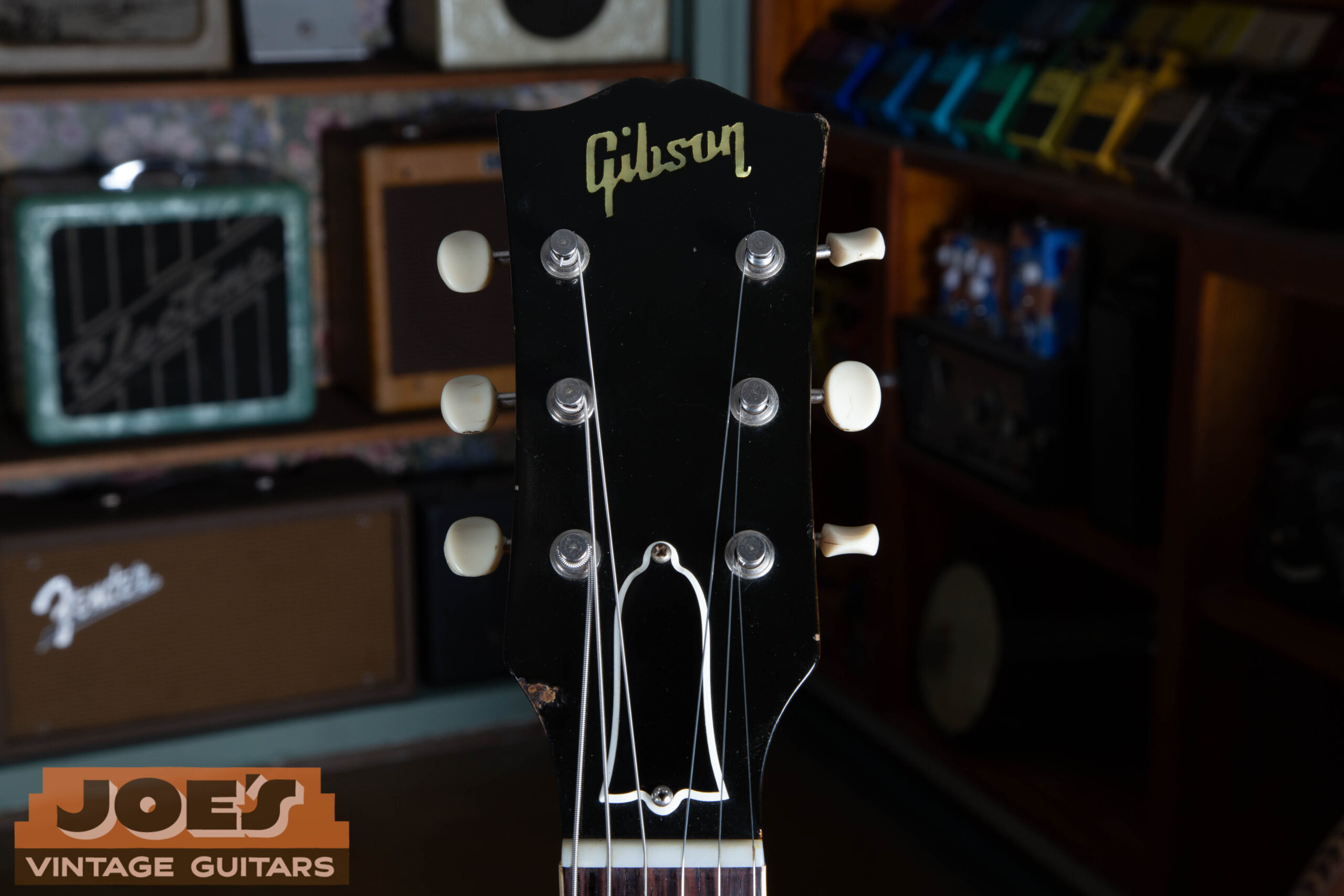 Front of headstock on a 1959 Gibson ES-330 — plain unbound black face with pearl script logo and no crown inlay