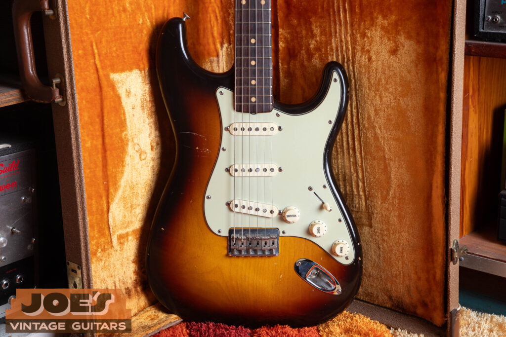 Front-facing body shot of a vintage 1960 Fender Stratocaster hardtail in a faded three-color sunburst finish, highlighting the fixed bridge plate and lack of a tremolo arm hole.