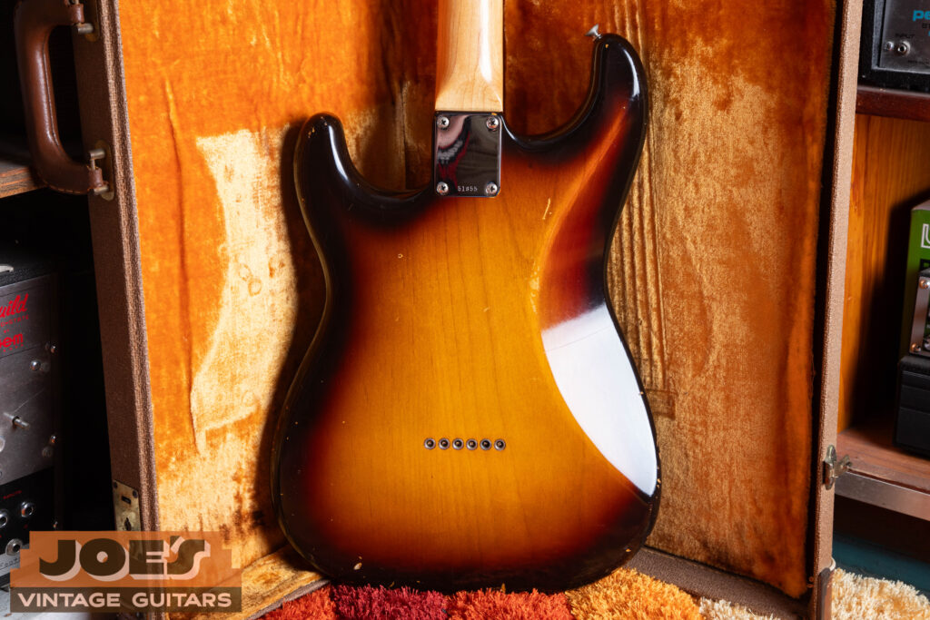 Rear view of a vintage Fender Stratocaster hardtail body showing the solid wood construction with six chrome string-through-body ferrules and the absence of a tremolo spring cavity or plastic backplate.