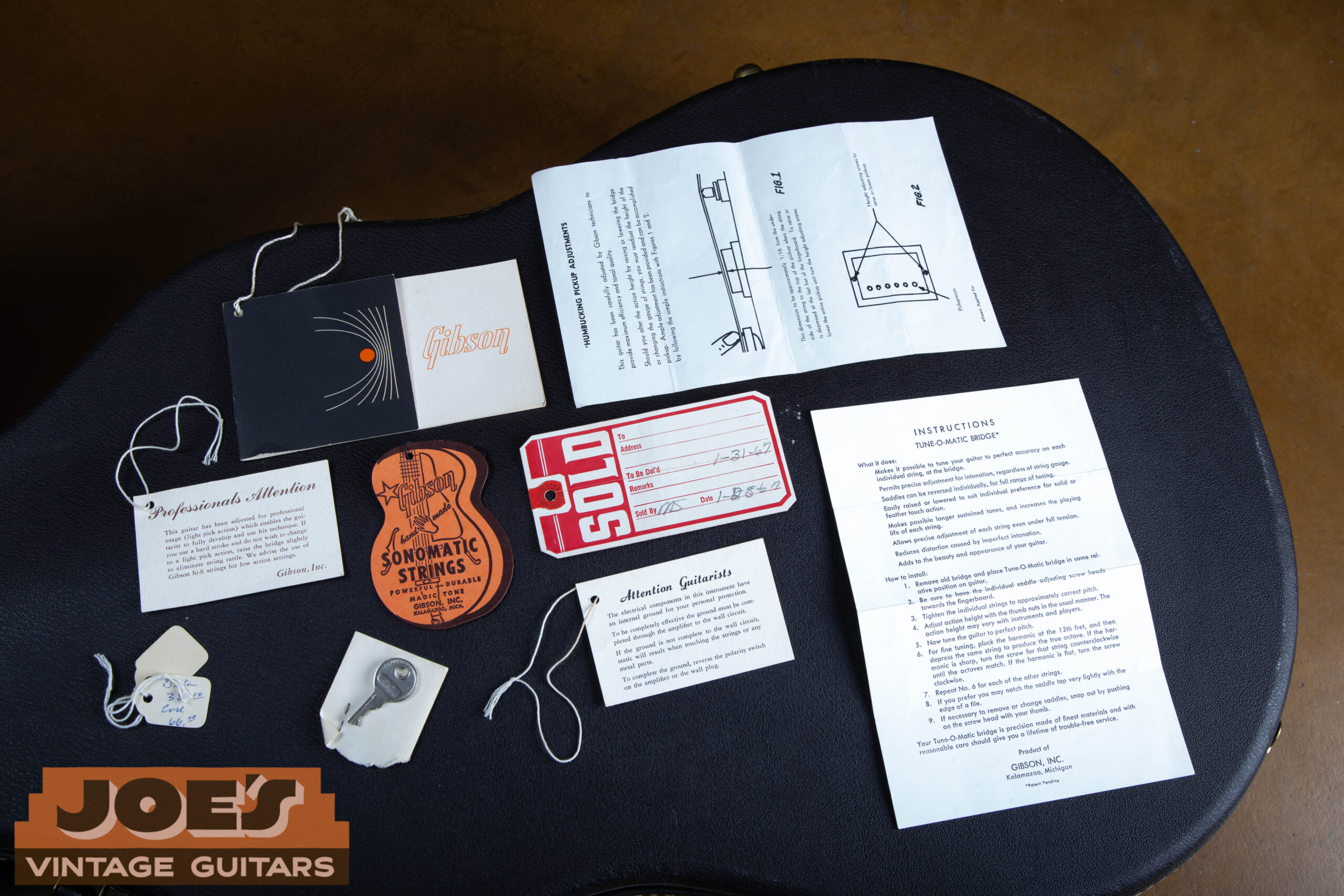 1966 Gibson ES-335 complete case candy collection — Tune-o-matic instructions, humbucking pickup sheet, attention guitarists tag, Sonomatic strings, Gibson booklet, adjustment tag, original key and price tag