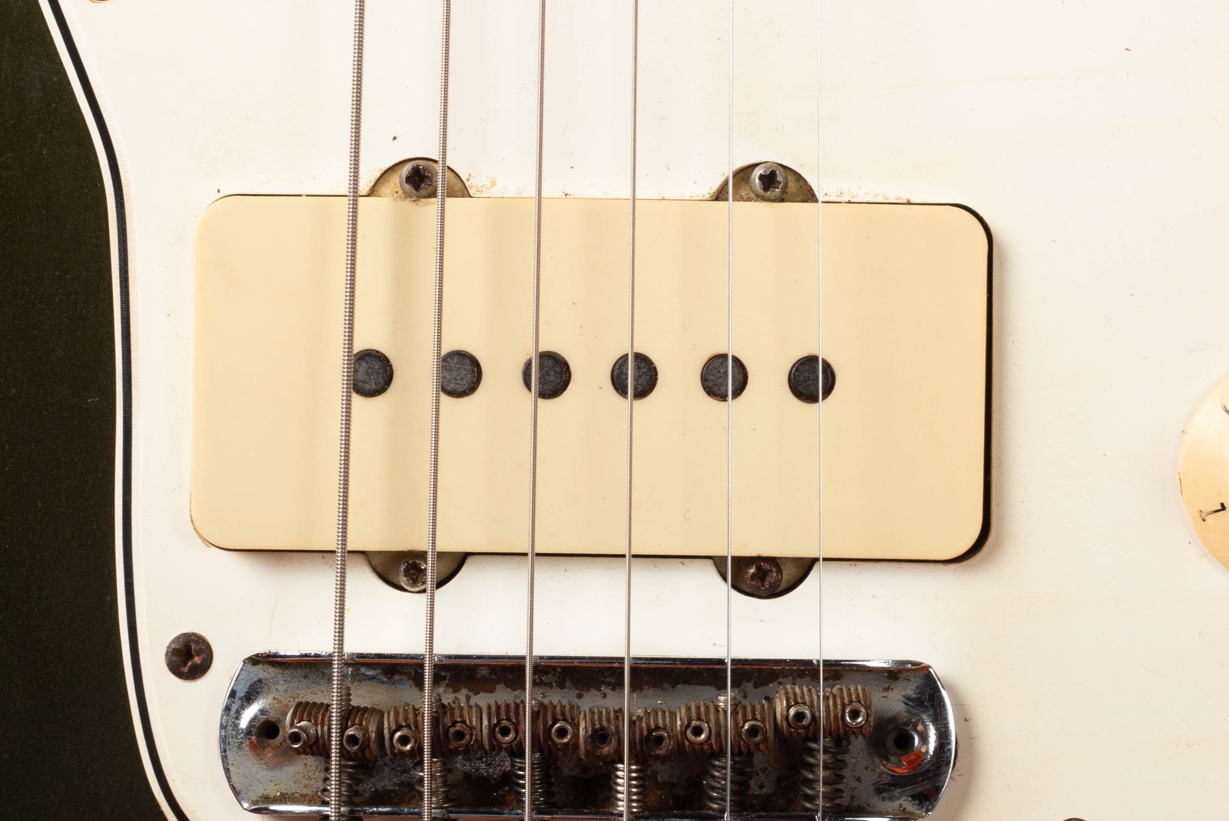 Fender Jazzmaster pickup close-up — wide flat single-coil pickup with chrome cover flush-mounted to pickguard, no exposed pole pieces, 1966 CBS-era example