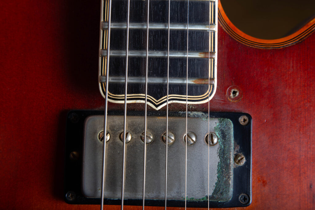 Close-up of the pointed ebony fingerboard extension on a 1969 Gibson L-5 CES. The image highlights the intricate multi-ply white and black binding, the dark grain of the ebony, and the craftsmanship where the neck meets the carved spruce top.