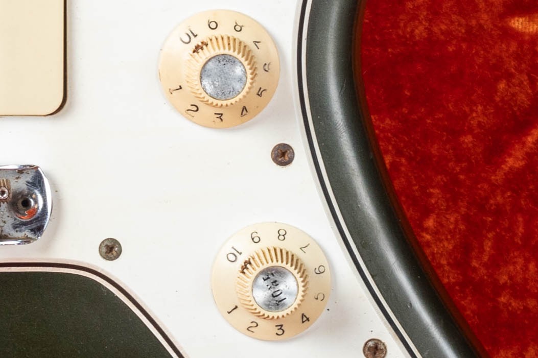 Fender Jazzmaster witch hat knobs close-up — white plastic with chrome domed top, CBS era indicator introduced mid-1965 replacing Strat-style dome knobs