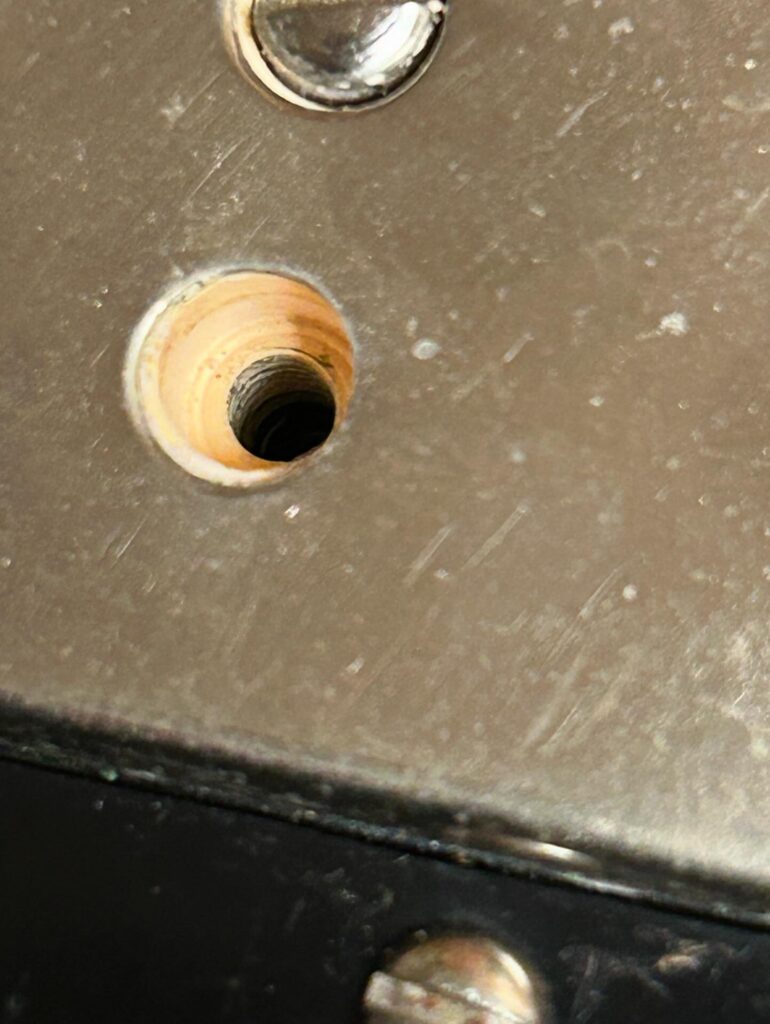 Close-up of a 1959 Gibson PAF humbucker with a pole piece screw removed to reveal the white bobbin