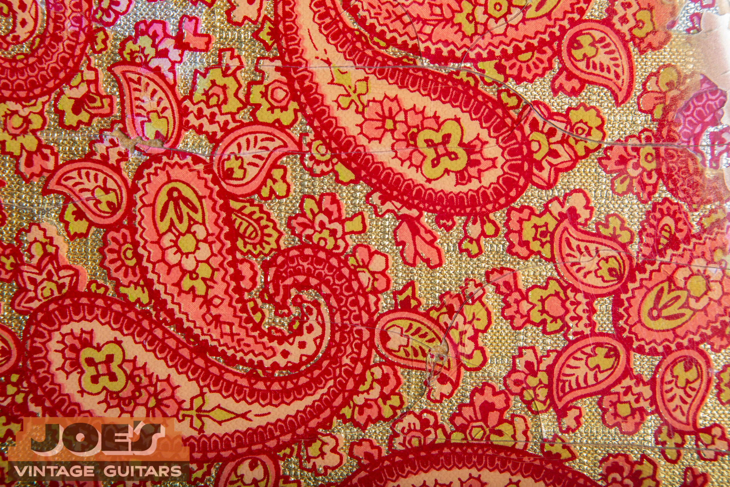 Close-up of the original Borden Cling-Foil paisley paper showing the printed pattern and reflective metallic aluminum sheen