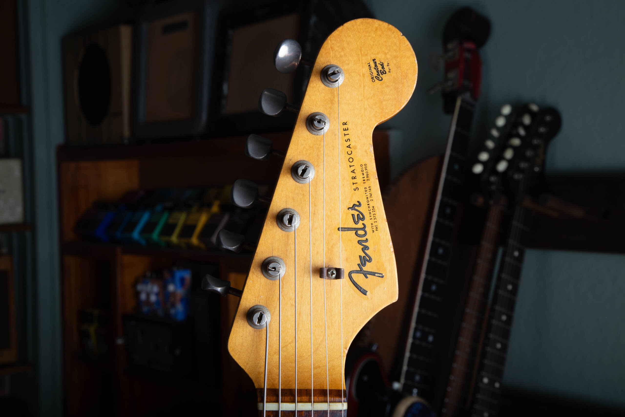 Front of the headstock on a 1963 Fender Stratocaster showing the gold spaghetti logo and three patent numbers